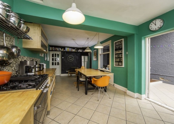 11. spacious family kitchen with vibrant green walls and wooden units