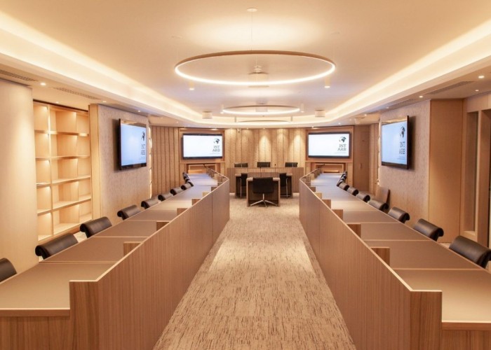 8. Contemporary Office filming location featuring two rows of desks facing each other and top table and architectural features